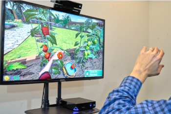 Image showing a user's arm controlling the SaeboVR virtual therapy game on a monitor.